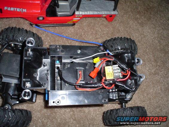 Remote control toy car chassis with exposed wiring and red body with FABTECH label