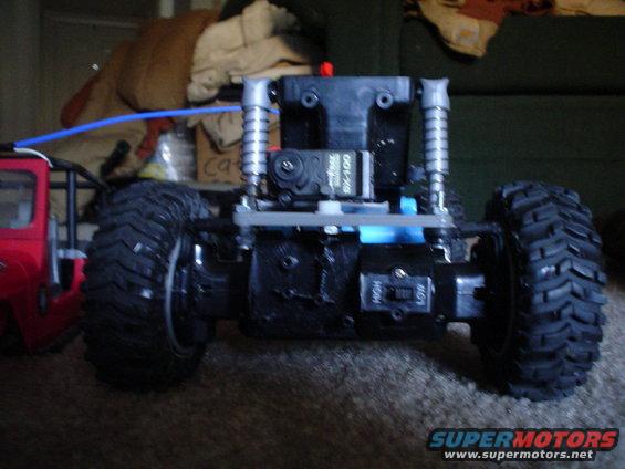 RC car chassis with large tires, red body on left. Servo motor visible