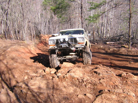 Off-road vehicle with winch and large tires navigating a rocky trail