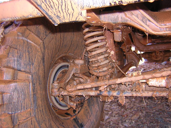 Mud-caked suspension and tire of an off-road vehicle