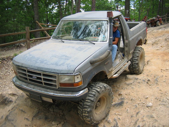 Modified 1992 Ford Bronco with snorkel and large tires on a rocky trail
