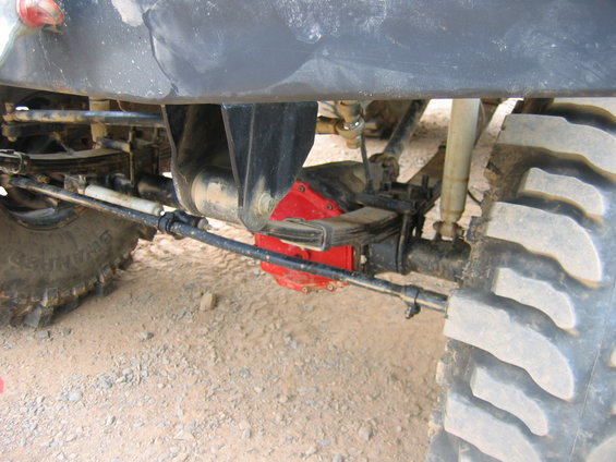 Close-up of off-road vehicle's rear axle, leaf springs, shock absorber, and large tire