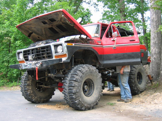 Lifted red and black Ford F-Series truck with hood and door open. Looks like it's being worked on