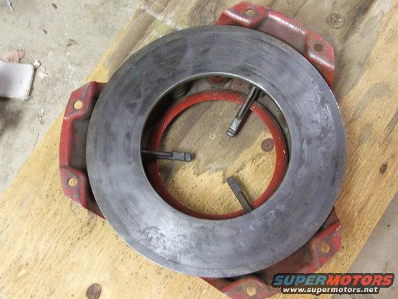 Clutch pressure plate with red diaphragm spring, on wooden surface