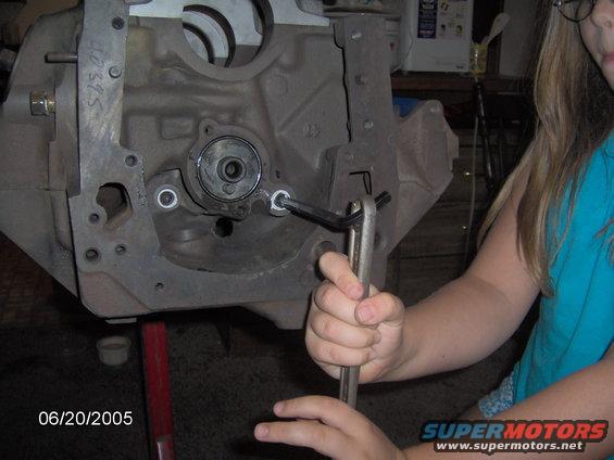 Close-up of an engine block with someone using a wrench on a bolt. Date stamp says 06/20/2005
