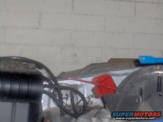 Engine bay with black air intake, red container, and hoses