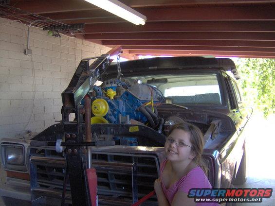 1978 Ford Bronco front view, engine hoist lifting blue engine, girl in pink shirt