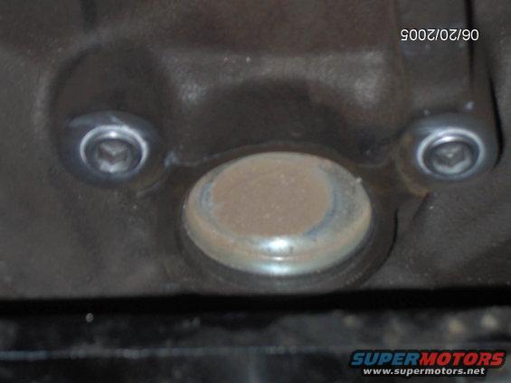 Engine part with two bolts and a circular cap. Date stamp 06/20/2005