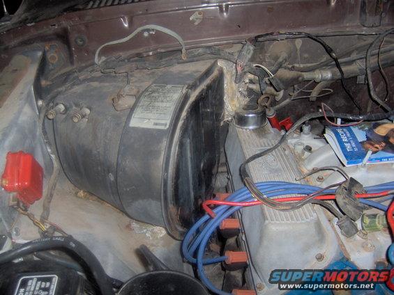 Engine bay showing a large black heater core housing and engine components with blue and red spark plug wires