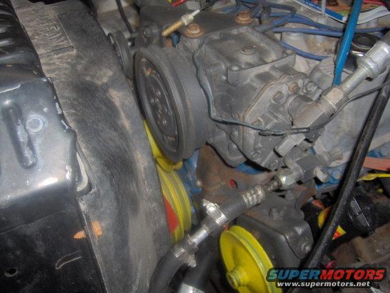 Engine bay with compressor, belts, and radiator fan. Some yellow pulleys are visible