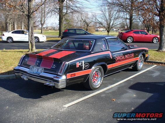Black Oldsmobile 442 W-30 pace car with red stripes and 'Official Pace Car' graphics parked in a lot