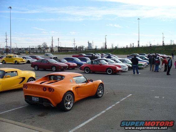 Parking lot filled with various cars, including an orange Lotus Elise in the foreground