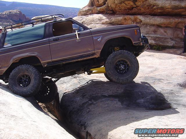 Brown 1986 Ford Bronco II climbing over rocks on a trail