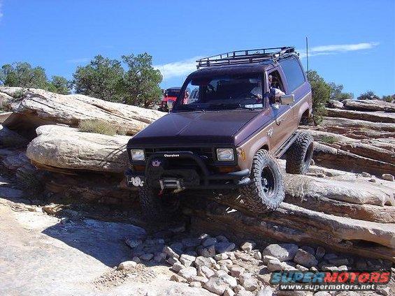 Brown and tan Ford Bronco II off-roading on rocks, front winch visible