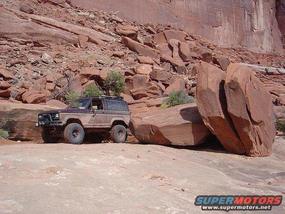 1986 Ford Bronco II parked on dirt trail next to large rocks in a canyon