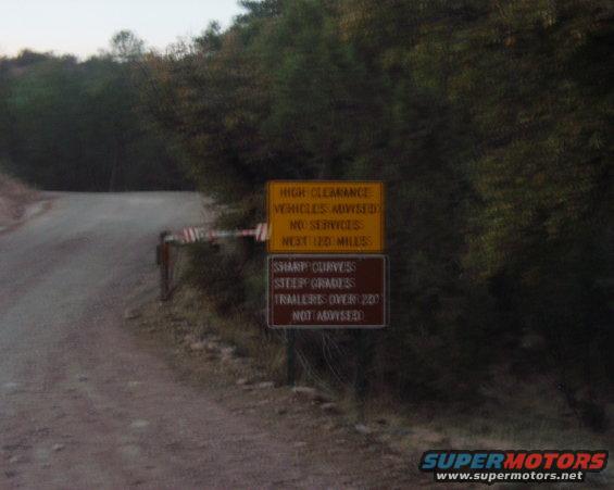 Roadside signs warn of high clearance, no services, sharp curves, and steep grades