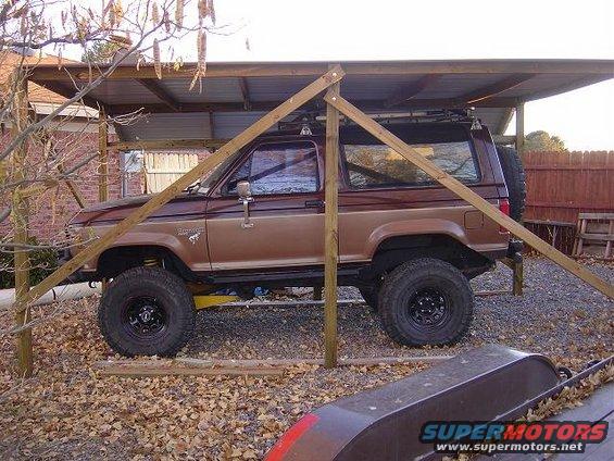 Brown Ford Bronco II parked under a makeshift shelter