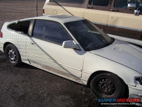 White Honda CRX with a broken rear window and dented side panel, parked outdoors