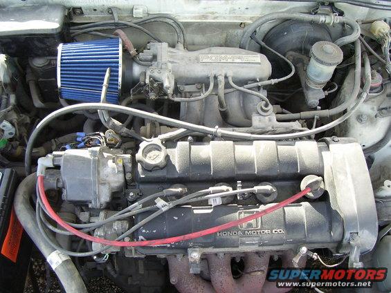 Engine bay with blue air filter and "HONDA MOTOR CO." on valve cover