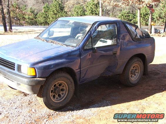 Blue pickup truck with a damaged driver's side door and a soft top rear