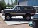 1988 Ford Bronco - A lifted Ford Bronco is parked outside a garage, with another vehicle visible in the background.