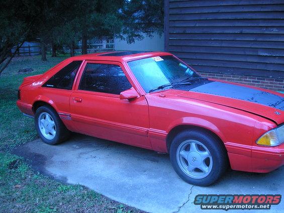 1989 Ford Mustang coupe, red with black hood and roof, parked on concrete