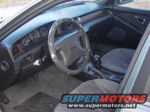 Interior view of a car with a camouflage steering wheel cover and SuperMotors watermark