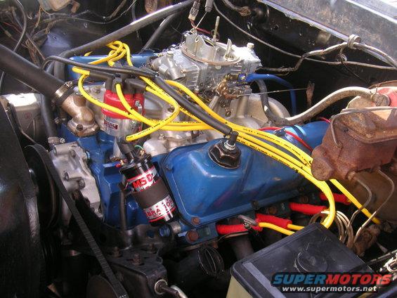 Engine bay with blue valve covers, yellow spark plug wires, and a red distributor cap