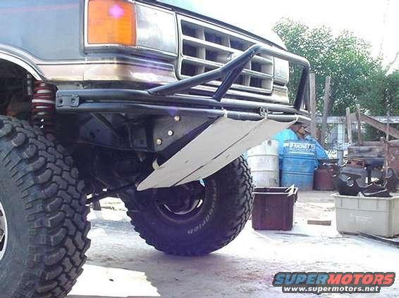 Front view of a truck's bumper and large tire. Grille is visible