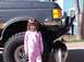 1988 Ford Bronco - A young girl poses in front of a dark gray Ford Bronco with a custom bumper and large tires.