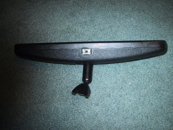 Black rear view mirror with a small square sensor on top and a broken mounting bracket
