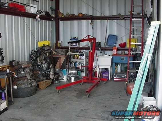 Engine and parts in a workshop with a red engine hoist