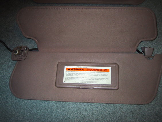 Tan car sun visors with a warning label about airbags and seatbelts