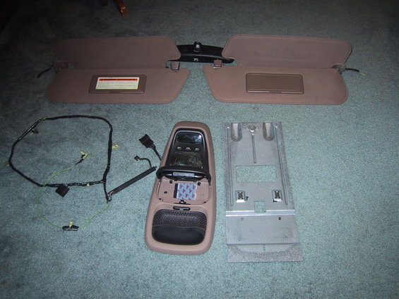 Overhead console, two sun visors, and wiring harness laid out on carpet