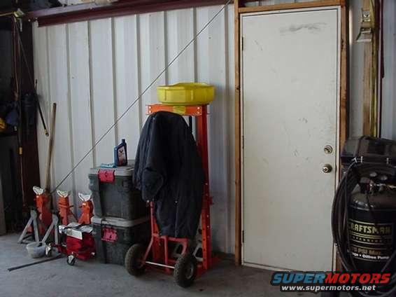 Garage interior with tool stands, oil bottle, and a covered item on a cart
