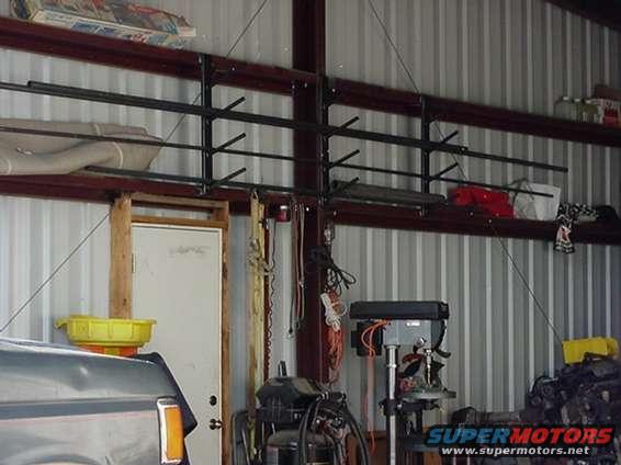 Part of a vehicle's interior and a storage rack with items on it inside a metal building