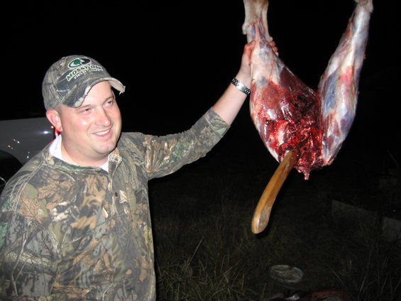 Man in camouflage holding a deer carcass