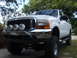 2000 Ford Excursion - White Ford Excursion with KC lights on a bull bar, parked outdoors.