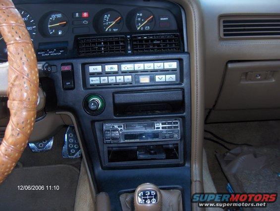 1986 Toyota Supra interior with tan leather steering wheel, dashboard gauges, and center console with radio and climate controls