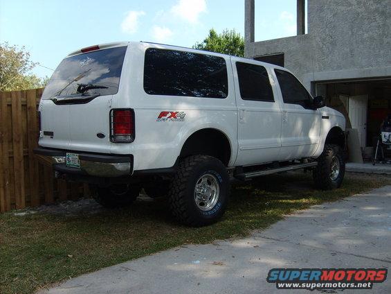 White Ford Excursion SUV, lifted, with FX4 Off-Road badging, seen from rear 3/4 angle