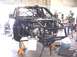 1988 Ford Bronco - Custom truck chassis undergoing modification in a workshop. Engine and roll cage are prominent features.