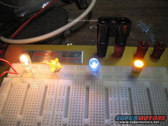 Breadboard with lit LEDs and bulbs, one labeled '194 bulb is the brightest'