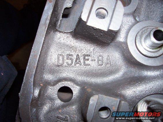 Close-up of a dark metal engine part with raised casting numbers D5AE-BA