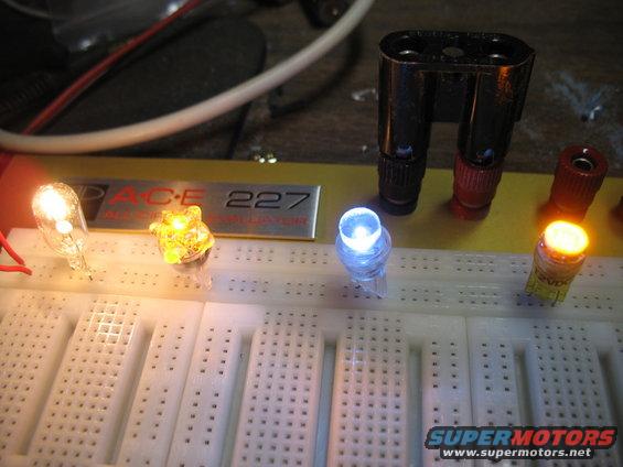 Breadboard with four LEDs lit in different colors, connected to wires and electronic components. A metal plate reads 'PACE 227'
