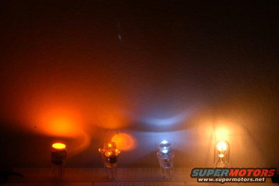 Four different colored light bulbs illuminated on a surface