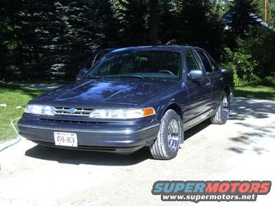 Dark blue sedan parked on a gravel driveway, front quarter view. License plate reads 498-HCV