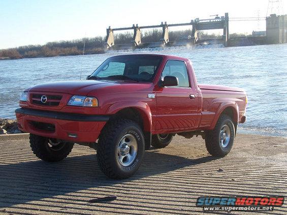 Red 2001 Mazda B3000 pickup truck parked by a dam