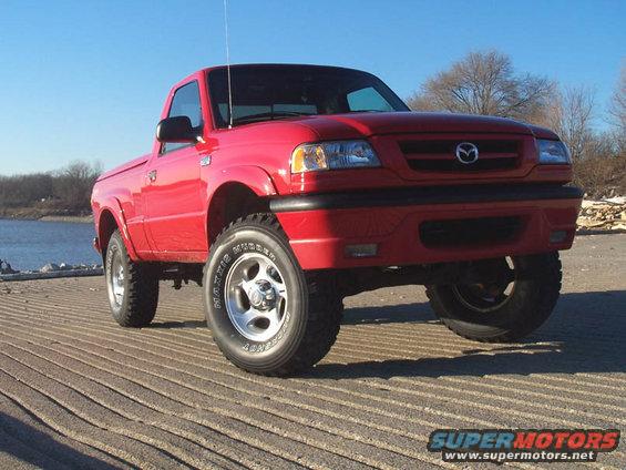 Red 2001 Mazda B3000 pickup truck parked on a ramp near water