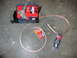 1992 Ford Mustang - A red Optima battery sits on a black mount next to coiled copper audio cables and a package of belts.