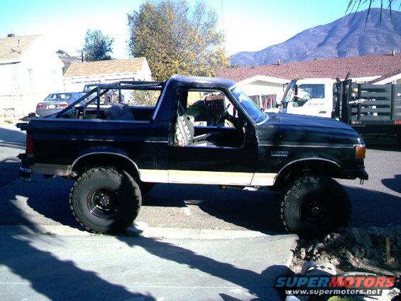 Black Ford Bronco with roll cage, lifted suspension, and off-road tires parked on a street
